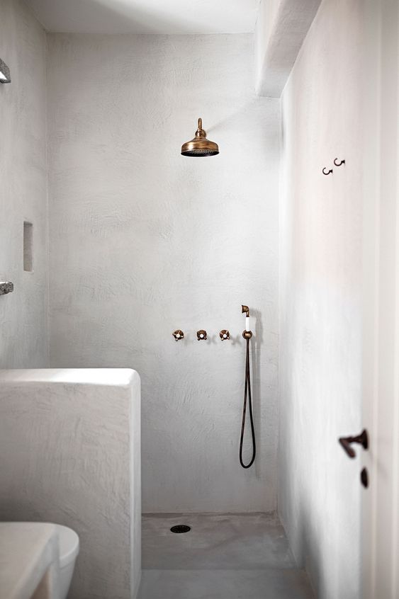 a plaster covered bathroom with a pony wall to divide the shower space from the rest