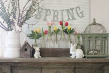 04 a rustic console with greenery, colorful tulips in clear vases and a spring banner