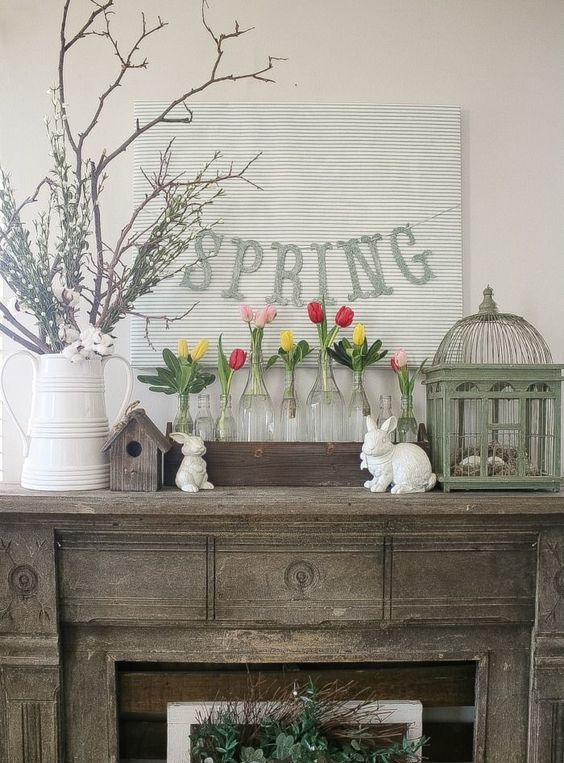 a rustic console with greenery, colorful tulips in clear vases and a spring banner