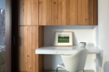05 The home office nook is done with wood clad cabinets and a floating desk with a comfy chair