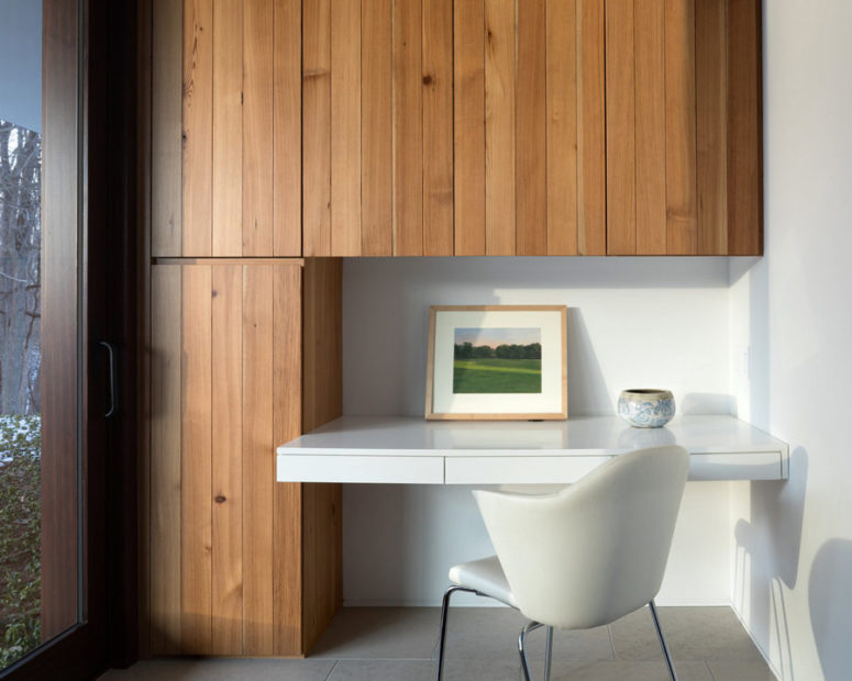 The home office nook is done with wood clad cabinets and a floating desk with a comfy chair
