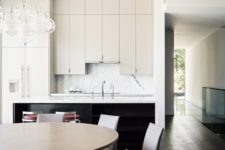05 The kitchen and dining space are united, there are upper cabinets of different height, a marble backsplash and modern leather chairs