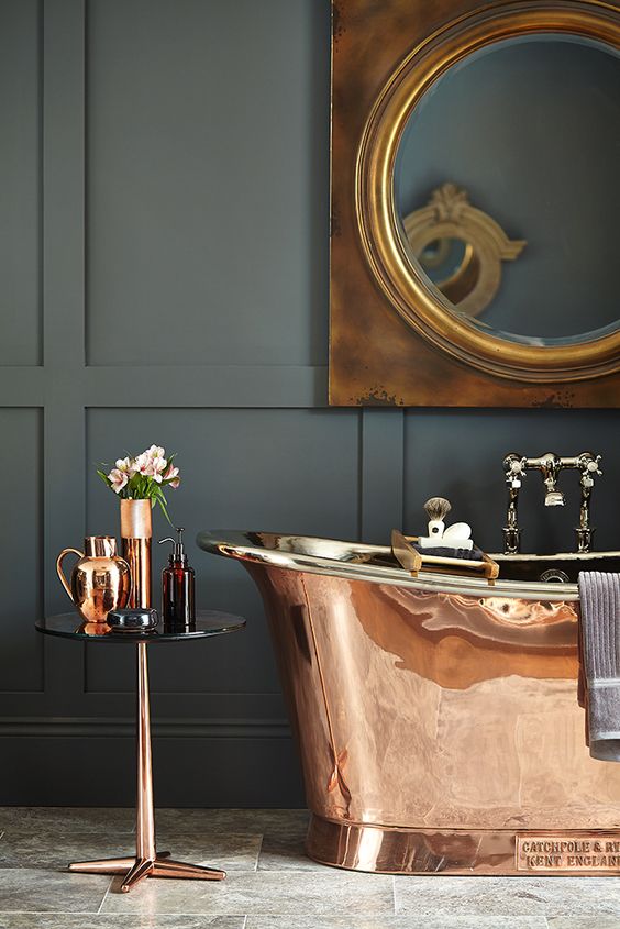 a brass free-standing bathtub, a matching table and vases for a refined and catchy look