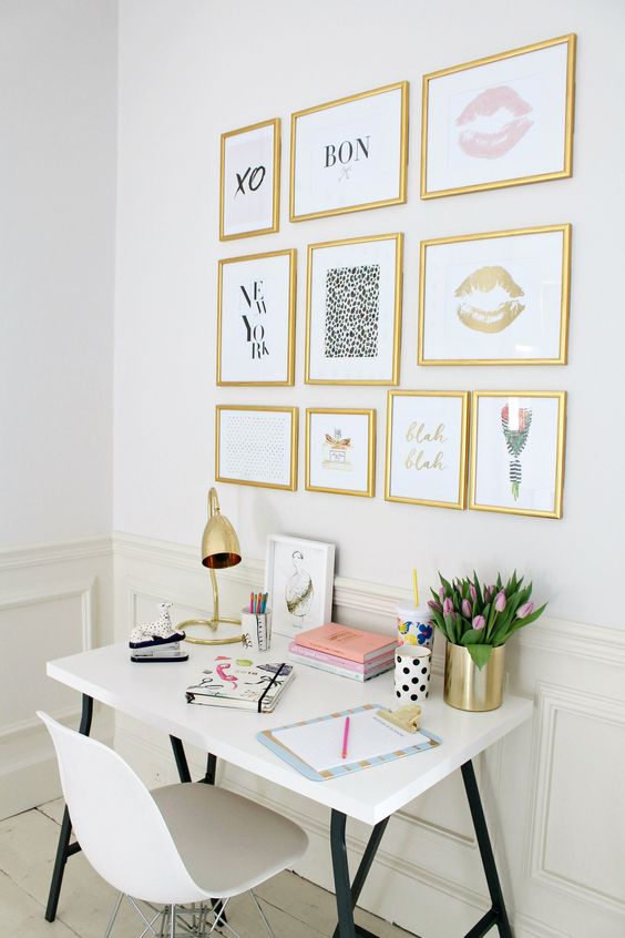 A girlish workspace with a gallery wall with gold frames and various girlish art