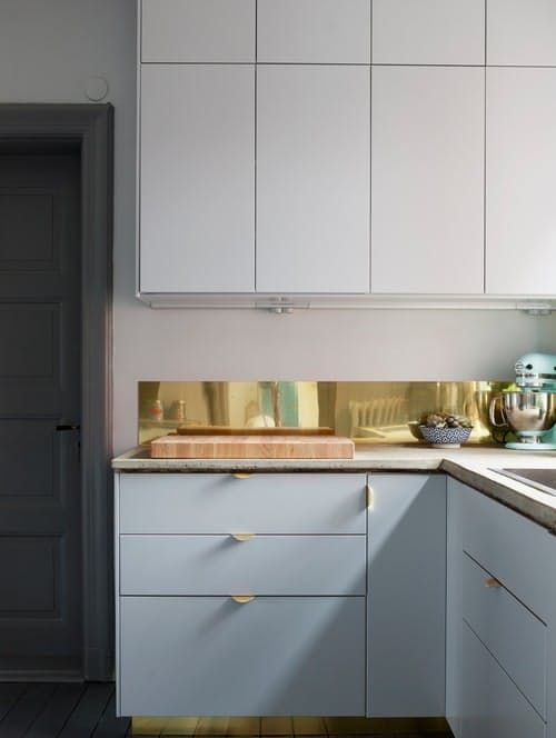 a narrow polished gold kitchen backsplash to add interesting to a plain white kitchen