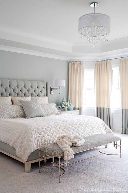 a serene bedroom in blush and grey, with a glam chandelier and a refined bench at the foot