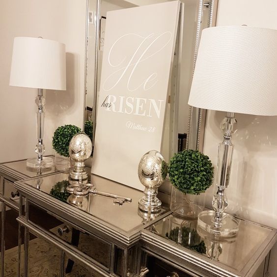 an elegant console table with mercury glass eggs and boxwood balls plus a poster