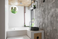 07 The bathroom is done with fresh greenery, industrial touches and a platform with storage, which incorporates a bathtub