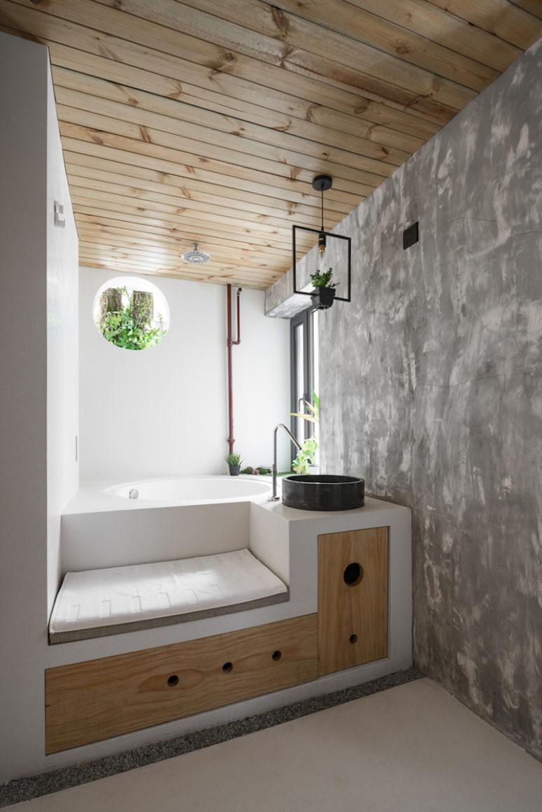 The bathroom is done with fresh greenery, industrial touches and a platform with storage, which incorporates a bathtub
