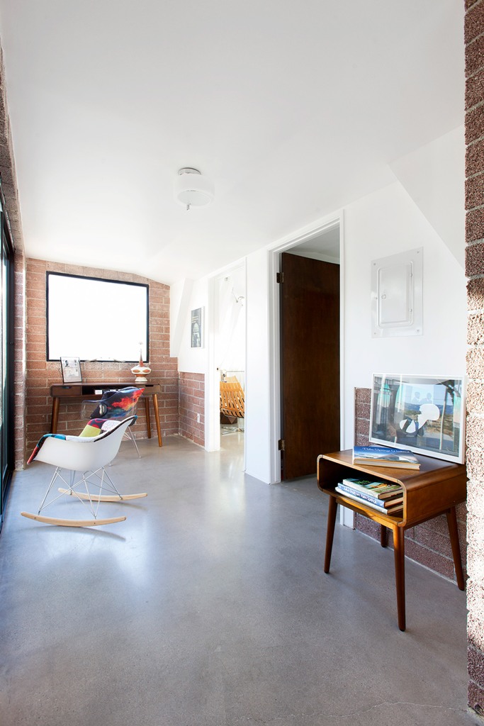 The home office is done with brick walls, mid-century modern furniture and is filled with natural light