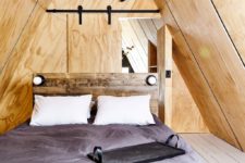 07 The master bedroom is clad with plywood, there’s a barn door and a reclaimed wood bed, there’s nothing unnecessary