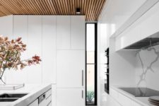 07 a sleek minimalist white space is accented with a wood slab ceiling and a large skylight for a natural feel