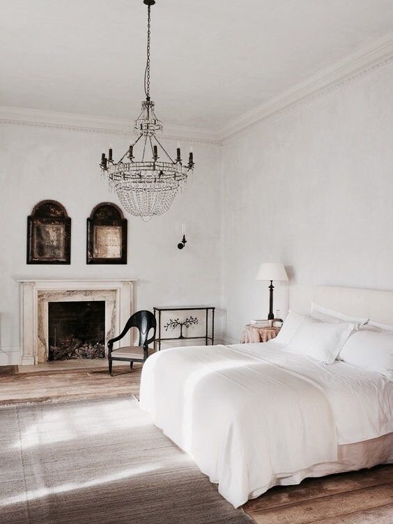 a vintage bedroom with a large crystal chandelier and fireplace and mid-century modern furniture