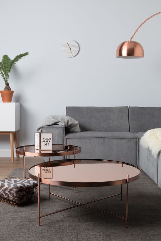 matching polished copper tables and a floor lamp add chic and brightness to the space