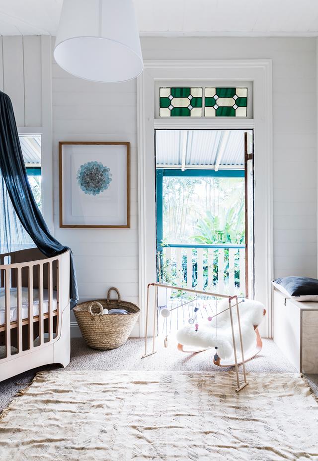 The nursery shows off a stunning modern crib with a dark canopy, some matching navy touches and cozy accessories