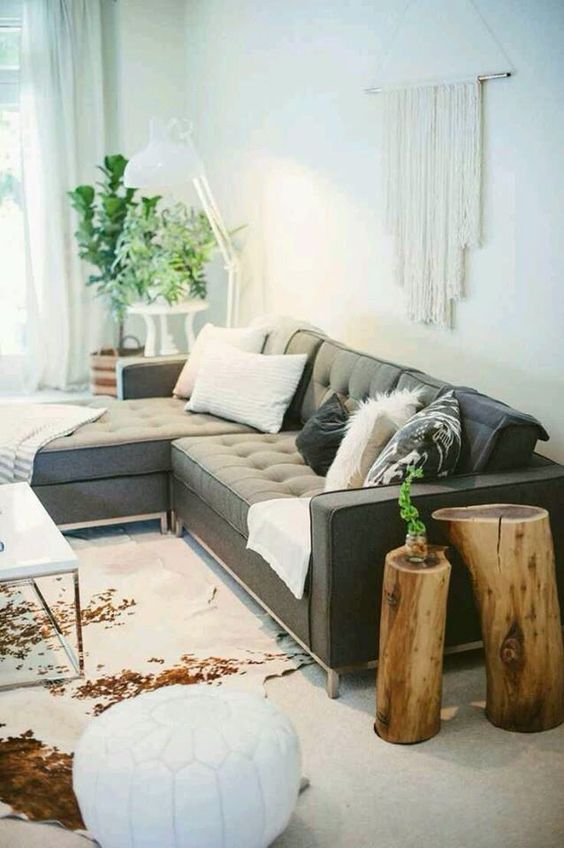 A boho chic space with a large grey secctional sofa that makes the base of the room