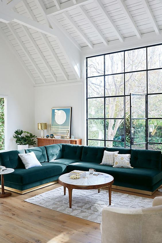A large teal velvet L shaped sectional sofa is a statement piece in this airy space