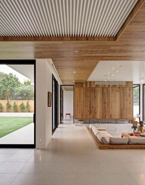 a sleek wooden ceiling adds texture and is continued in a wood clad fireplace wall