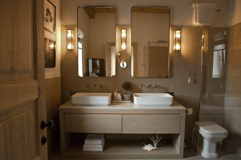 The master bathroom is clad with light-colored tiles and wooden vanity, there's a shower and a double sink
