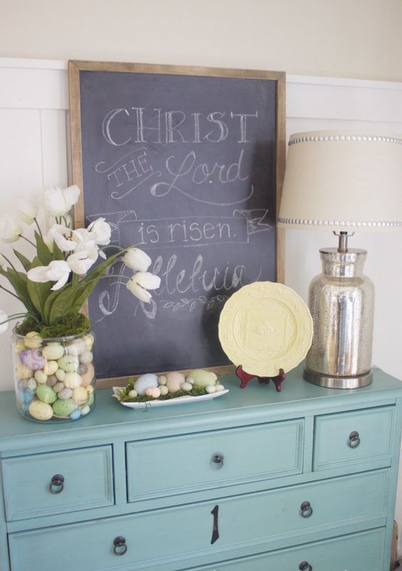a chalkboard sign, pastel eggs in the tray and a large glass pot with moss, pastel eggs and white tulips