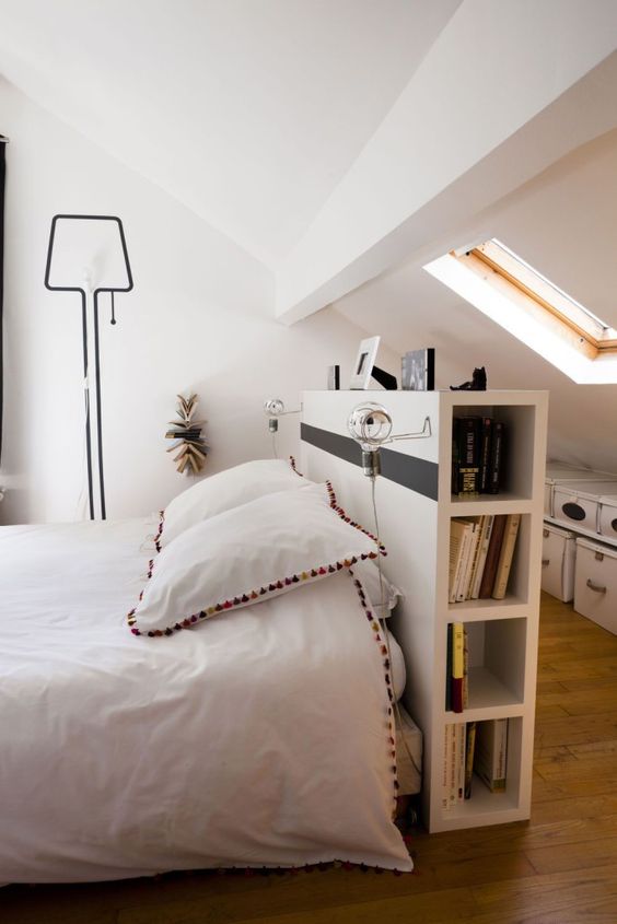 a pony wall acts as a headboard and a storage unit in the bedroom and divides the sleeping space and the closet