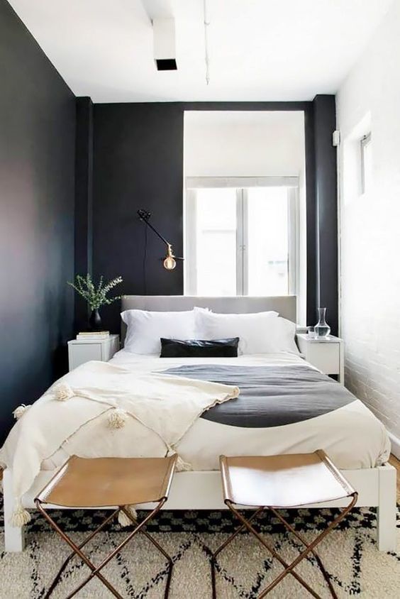 a small bedroom with a large bed and black and white walls looks bigger than it could