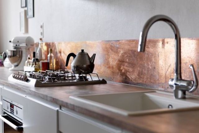 Shiny copper metal backsplash adds eye catchiness to the kitchen and a cool feel