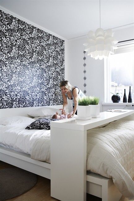 a modern bedroom with a printed headboard wall and a comfy bench and caddy for functionality