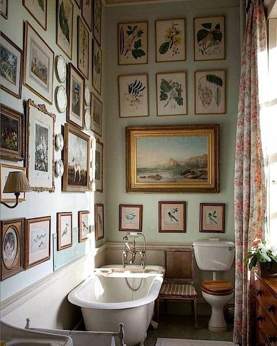 a small vintage bathroom is given a living room feel with lots of artworks and sconces