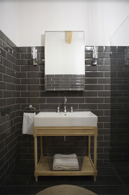 The powder room is clad with graphite grey tiles accented with white grout