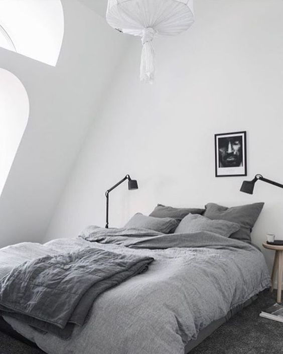 a comfy and small Scandinavian attic bedroom with a grey bed and some lamps - nothing else is needed here