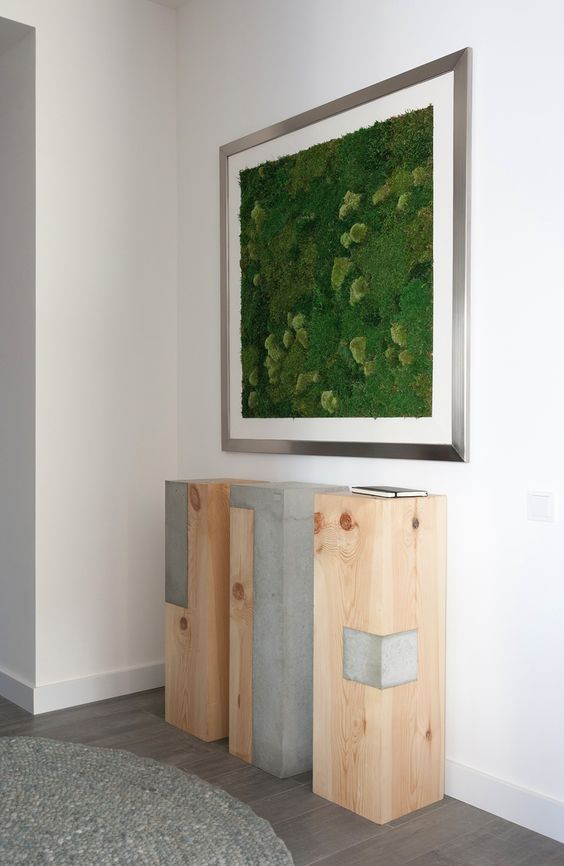 a framed moss wall art over an industrial three-piece console is a bold modern idea