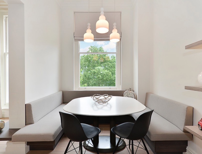 A tiny dining space features built in banquettes and a rounded table that don't make the space feel small