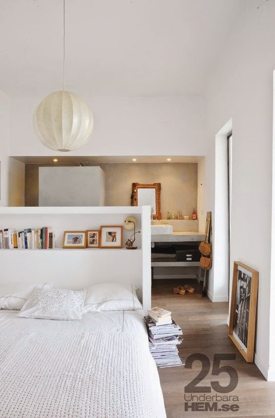 a white pony wall features a storage shelf and works as a headboard, there's a bathroom space below