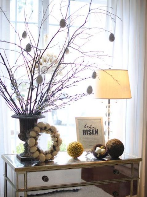 a mirrored console with an egg wreath, an Easter tree with egg ornaments and moss balls and a nest