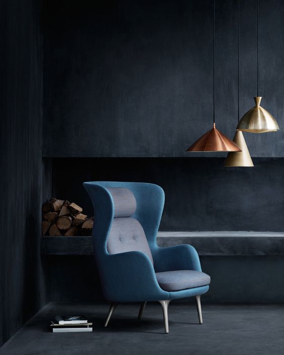 A bold wingback chair with a mid century modern twist in grey and blue is a show stopper in this moody space