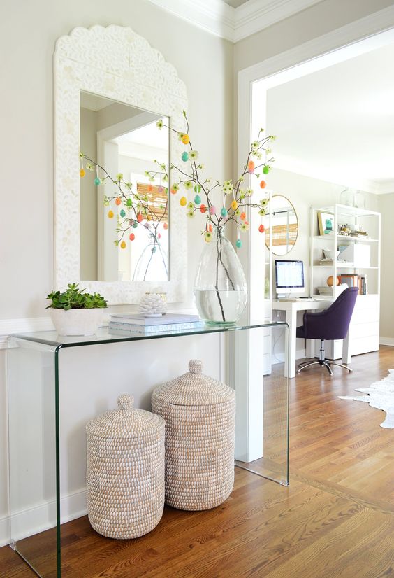 a modern acrylic console with potted succulents and an Easter tree with colorful egg ornaments