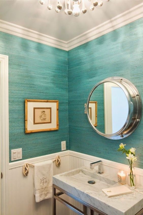 An ocean inspired bathroom with wainscoting that protects the wallpaper and makes the bathroom feel vintage