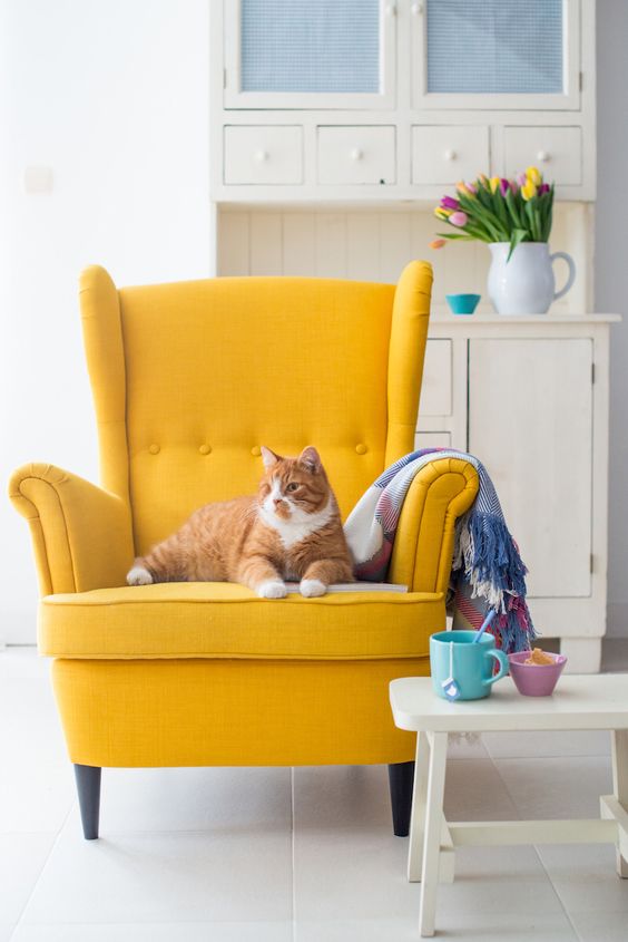 a bold yellow wingback brings a cheerful feel and colorful touch to the space