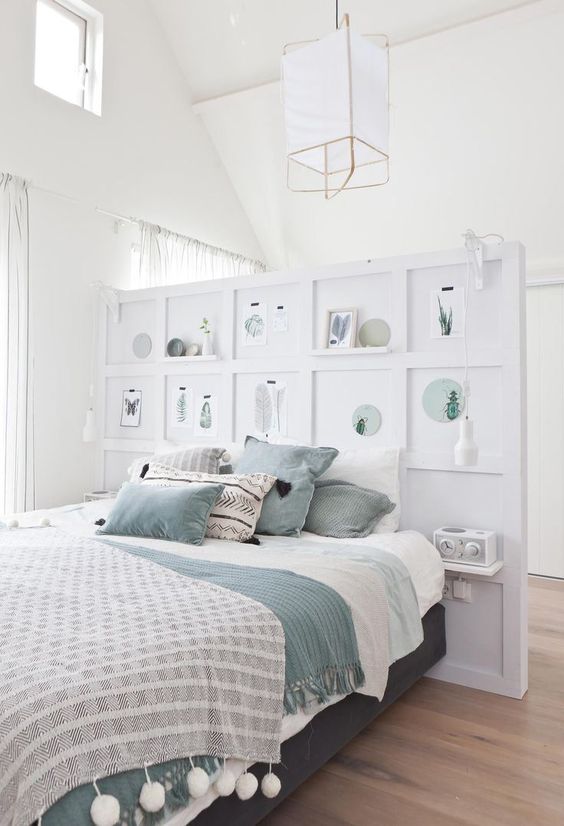 a pony wall with shelves and artworks as a decorative element and a divider for the sleeping and dressing space