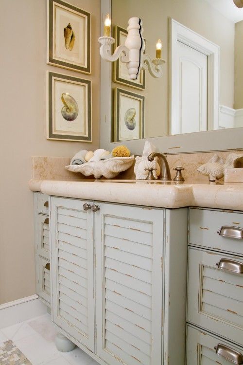 A sink vanity made of old pastel colored shutters and a stone countertop for a beach inspired bathroom