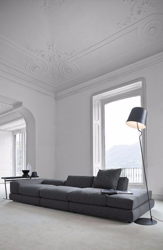 the whole large space is done in white, with a dark grey sofa and lamp, with lots of no decor space