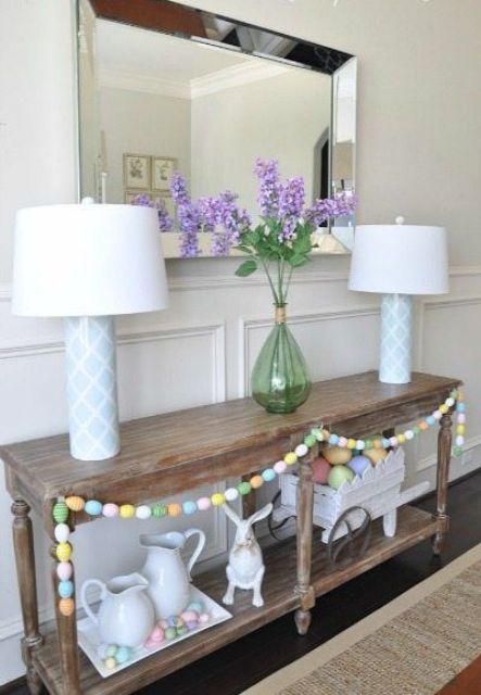 a rustic wooden console decorated with a colorful egg garland, a tray with eggs and a bunny