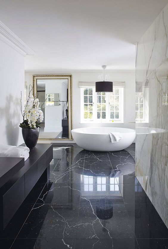 an oversized framed wall mirror adds more glam and chic to this marble bathroom