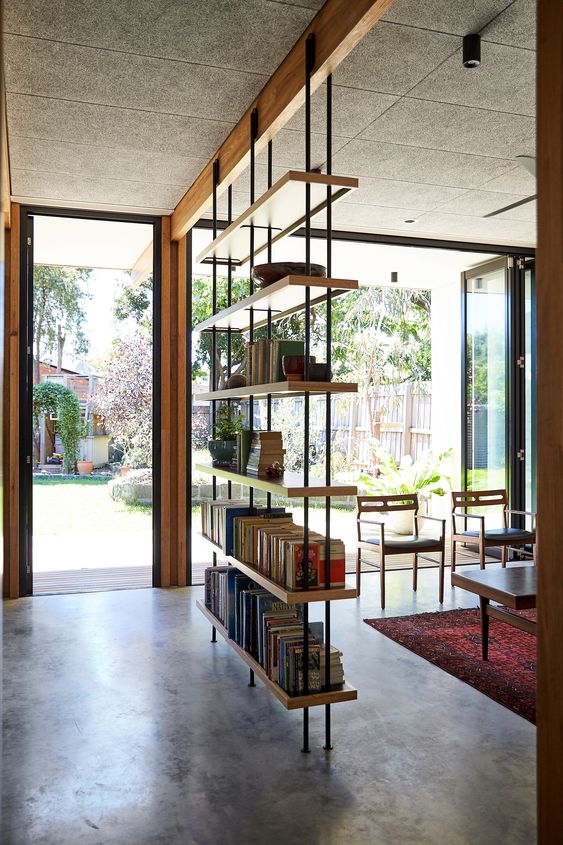 an industrial bookshelf of metal and plywood is a great lightweight piece to separate the spaces