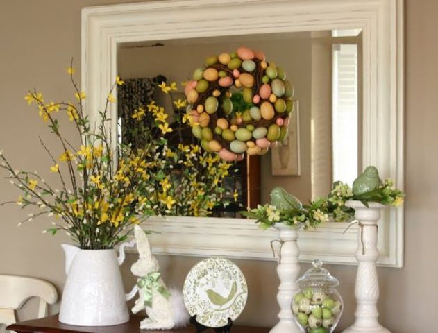 an Easter console with faux blooming branches, a colorful egg wreath, colorful eggs in a jar