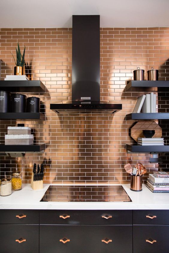 a copper tile backsplash and matching handles in a black kitchen to bring some chic