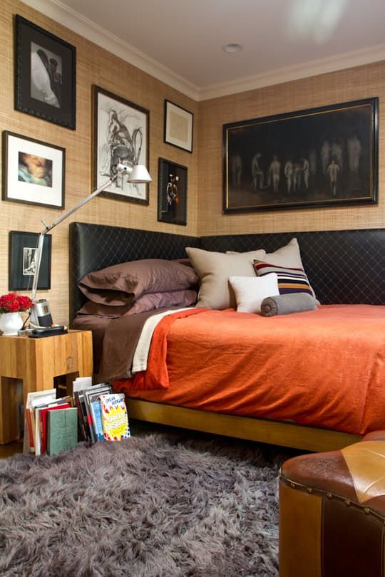 a moody bedroom with a corner headboard, colorful touches and lots of artworks