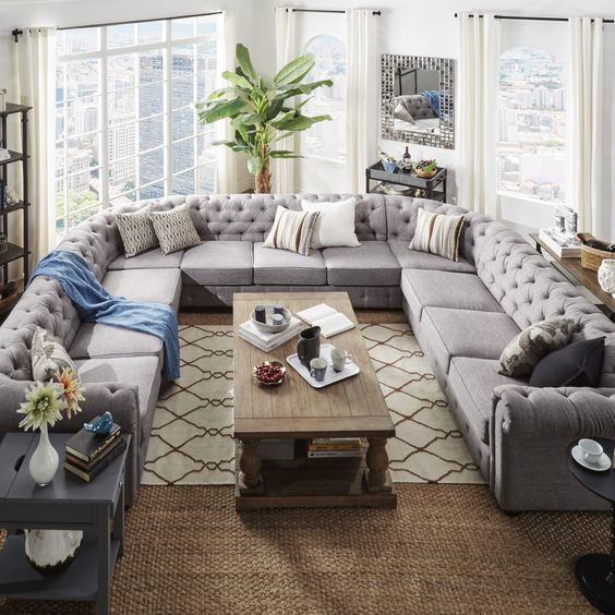 An oversized U shaped grey tufted sofa makes a perfect fit for this unusually shaped living room