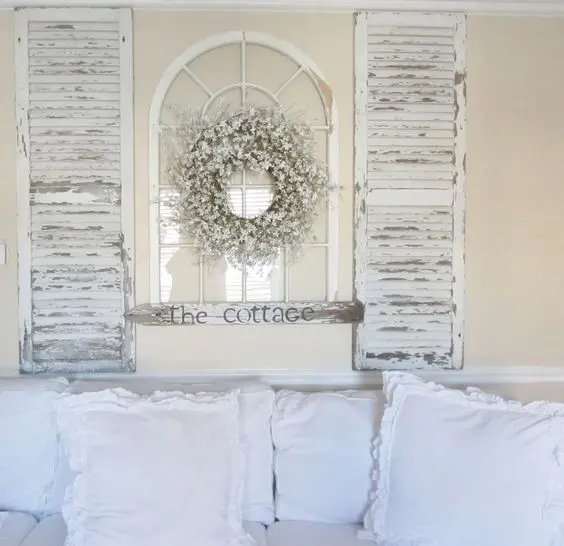 a shabby chic decoration of old shutters and a vintage window plus a floral wreath for a vintage space